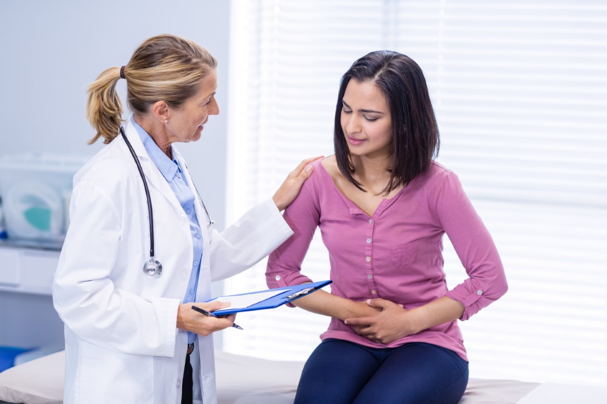 Patient suffering from stomach ache while consulting doctor in clinic