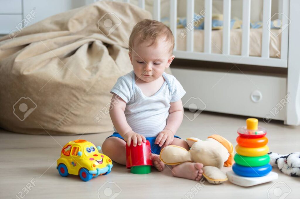 10 months old baby boy sitting on floor and playing with toys