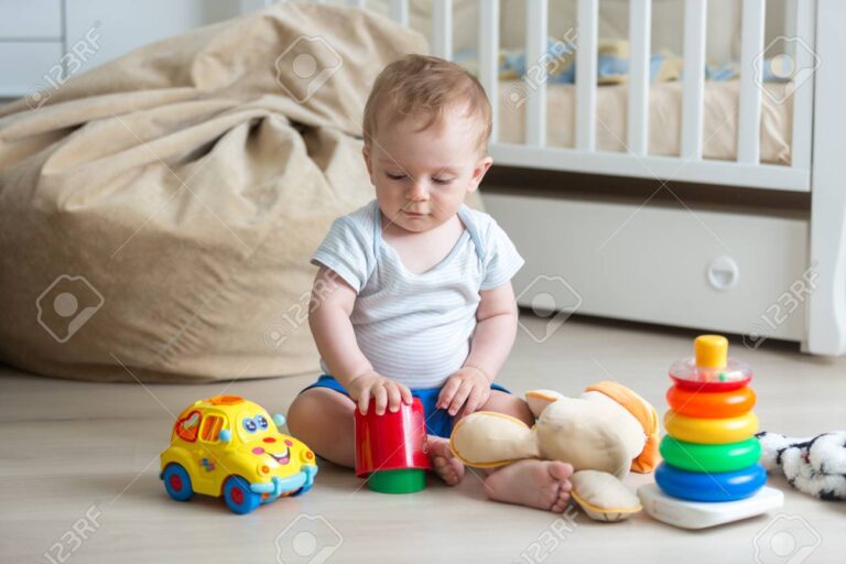 10 months old baby boy sitting on floor and playing with toys